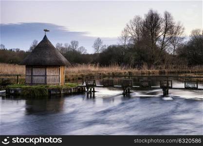 71428927 - beautiful landscape on winter morning of eel traps over flowing river in english countryside