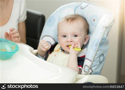 9 months baby boy with spoon sitting in highchair
