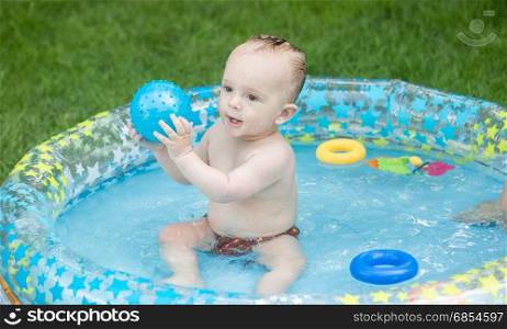 9 months old baby boy playing in pool outdoors