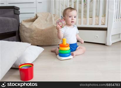 9 months old baby boy playing on floor with toy tower