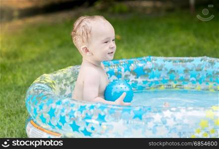 9 months old baby boy playing with ball in pool at garden