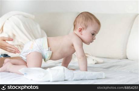 9 months old baby in diapers crawling on bed
