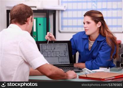 a 25 years old woman showing a draw on a computer to a man
