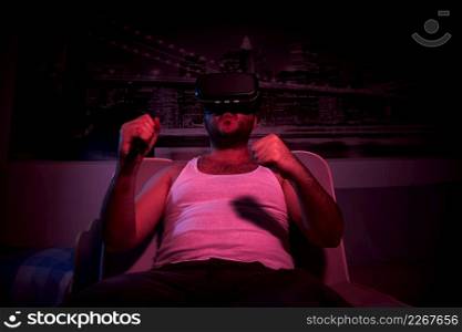 A 40-year-old unshaven overweight man watches TV with VR glasses, shows various emotions, gets angry. lazy middle-aged man.. A 40-year-old unshaven overweight man watches TV with VR glasses, shows various emotions, gets angry. lazy middle-aged man