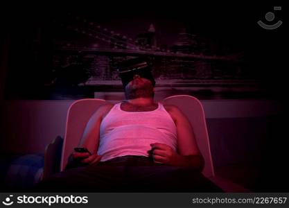 A 40-year-old unshaven overweight man watches TV with VR glasses, shows various emotions, sleeps . lazy middle-aged man.. A 40-year-old unshaven overweight man watches TV with VR glasses, shows various emotions, sleeps . lazy middle-aged man