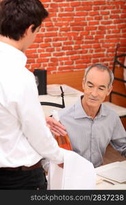 a 65 years old man looking a wine bottle presented by a wine waiter