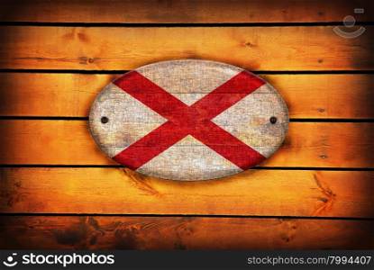 A Alabama flag on brown wooden planks.