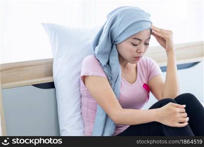 a asian women disease mammary cancer patient Have a headaches stick pink ribbon wearing headscarf After treatment to chemotherapy sit on bed In the bedroom at the house,healthcare,medicine