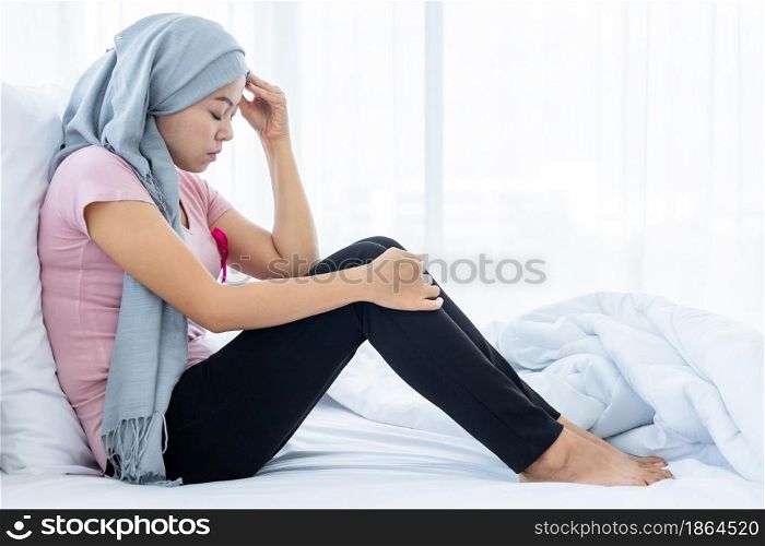 a asian women disease mammary cancer patient Have a headaches stick pink ribbon wearing headscarf After treatment to chemotherapy sit on bed In the bedroom at the house,healthcare,medicine