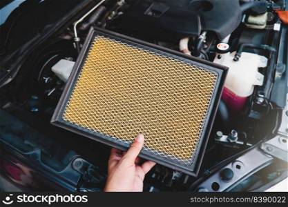 A auto mechanic carries a replacement car air filter for car engine maintenance