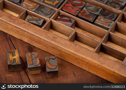 A, B and C letters in vintgae wooden letterpress type (Abbey typeface) with old typesetter case in background, image can be flipped in horizontal for original view of printing blocks