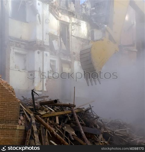 A backhoe emerging from the dust cloud to knock down the walls of a historic apartment building.