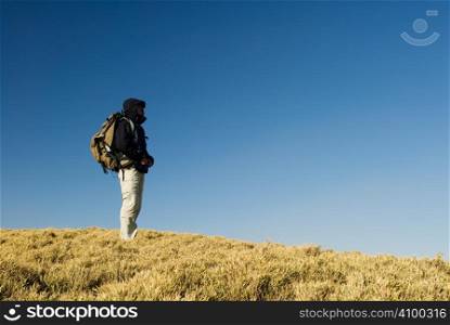 A backpacker walk on a yellow grassland in mountain.