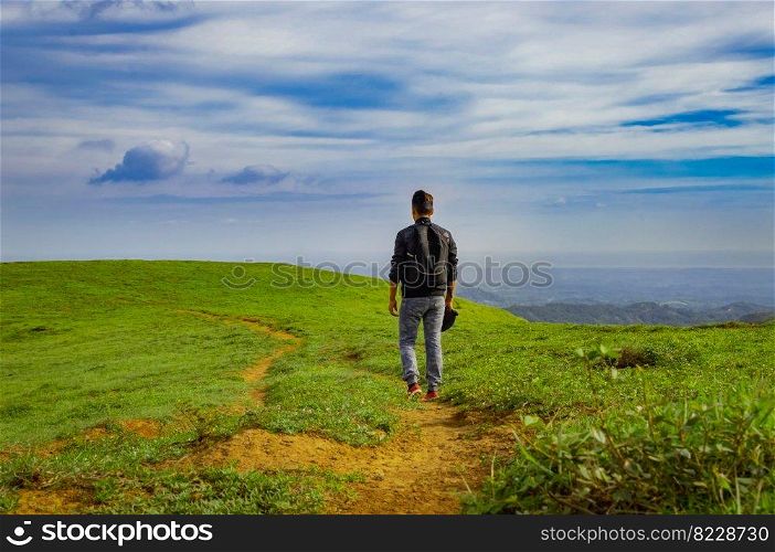 A backpacker walking on a hill with blue sky and copy space, man backpacking on a hill and blue sky background with copy space, successful man concept.
