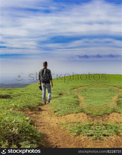 A backpacker walking on a hill with blue sky and copy space, man backpacking on a hill and blue sky background with copy space, successful man concept. 