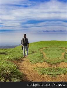 A backpacker walking on a hill with blue sky and copy space, man backpacking on a hill and blue sky background with copy space, successful man concept.