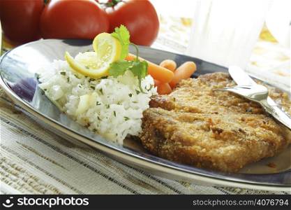 A baked pork chop with rice and carrots