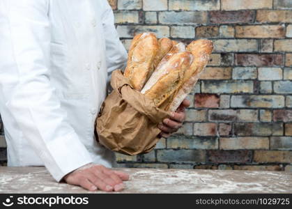 a baker holding traditional bread french baguettes