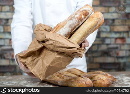 a baker holding traditional bread french baguettes