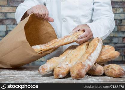 a baker holding traditional bread french baguettes