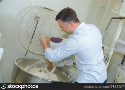 a baker is using industrial mixer