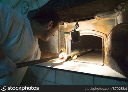 A baker removes freshly baked bread from his wood fire oven, Malta.