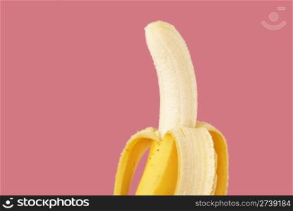 A banana ready for eating on pink background