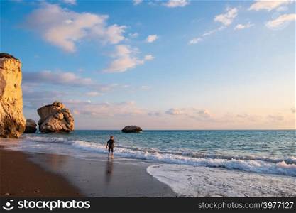 A barefooted boy plays at the beach againt the Petra tou Romiou rocks bathed in afternoon light, in Paphos, Cyprus. The beach is considered to be Aphrodite&rsquo;s birthplace in Greek mythology.