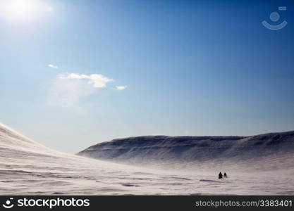 A barren winter landscape with two snowmobiles travelling accross the horizon