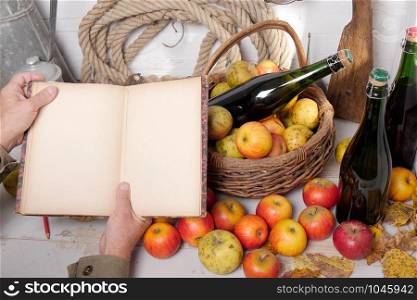 a basket of apples, bottles of cider and old notebook