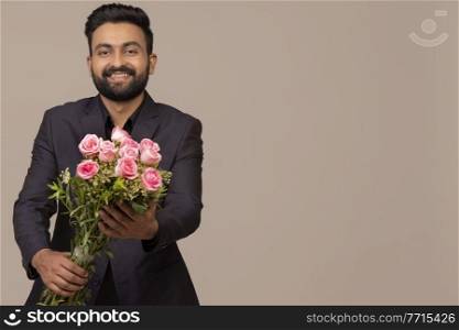 A BEARDED YOUNG MAN HAPPILY GIVING BOUQUET