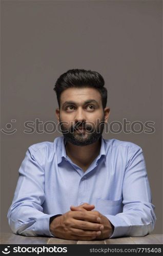 A BEARDED YOUNG MAN SITTING AND THINKING 