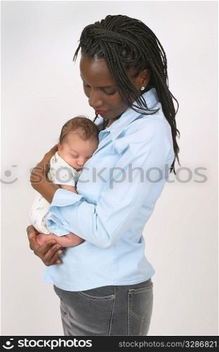 A beautiful African American lovingly holding a white or mixed race newborn child