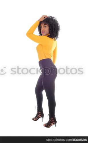A beautiful African American woman in black tights and yellow sweaterstanding full lengths in profile, isolated for white background.