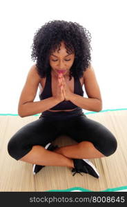A beautiful African American woman sitting on the floor with her handsfolded and curly black hair, isolated for white background.