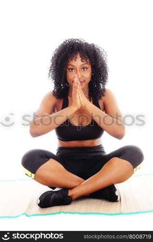 A beautiful African American woman sitting on the floor with her handsfolded and praying, isolated for white background.