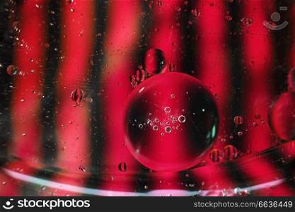 A beautiful and colorful vibrant macro of oil bubbles on water with a pink and black contrast as stripe texture and background pattern