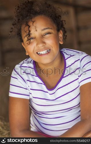 A beautiful and happy mixed race African American female girl child smiling sitting in hay filled barn