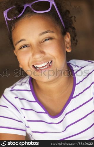A beautiful and happy smiling mixed race African American female girl child wearing sunglasses in golden sunshine and laughing