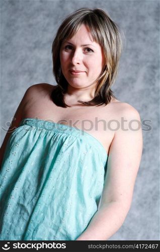 A beautiful and sexy 20-25 years blond girl in dress on grey background