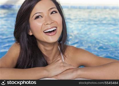 A beautiful and sexy young Chinese Asian woman wearing a white bikini leaning on side of a turquoise blue spa swimming pool. Healthy living and health club concept.