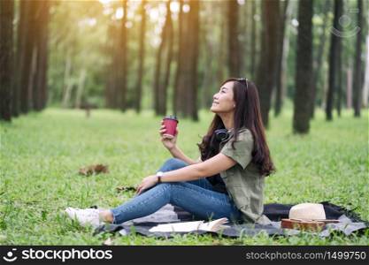 A beautiful asian woman drinking coffee while sitting in the park