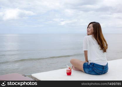 A beautiful asian woman drinking watermelon juice while sitting by the sea