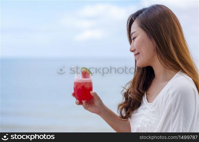 A beautiful asian woman drinking watermelon juice while sitting by the sea