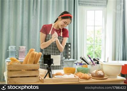 A Beautiful asian woman is making bakery ,   live streaming or recording video on social media in her house  