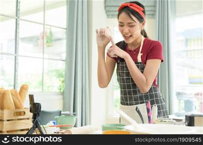 A Beautiful asian woman is making bakery , live streaming or recording video on social media in her house
