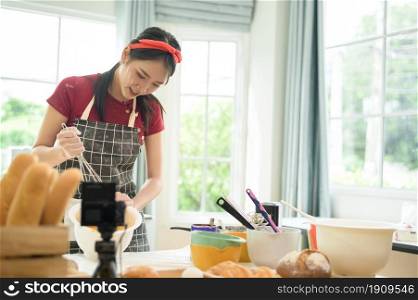 A Beautiful asian woman is making bakery , live streaming or recording video on social media in her house
