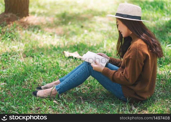 A beautiful Asian woman reading a book while sitting in the park
