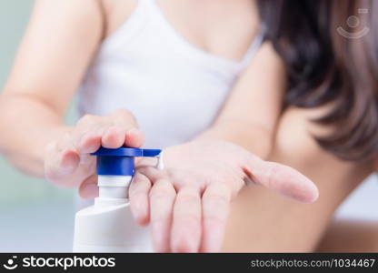 A beautiful Asian woman sitting on a bed pressing the cream Use body creams and lotions with care concepts.