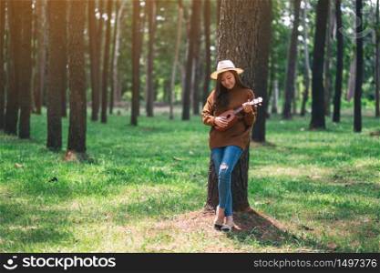A beautiful asian woman standing and playing ukulele in the park